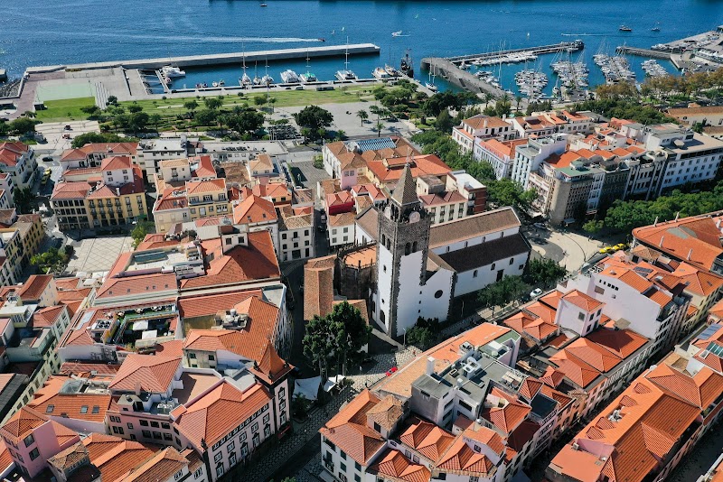 Aerial view of the coastal town reveals red-roofed buildings, a prominent church, and a lively marina. This picturesque scene is like a living map guide for tourists exploring its vibrant waterfront and charming streets.