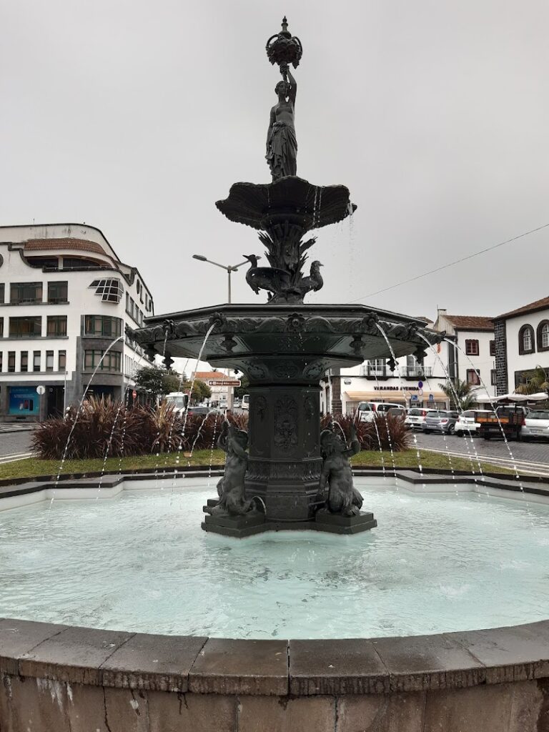 A multi-tiered fountain with statues, surrounded by buildings on a cloudy day, offers a picturesque spot that's often highlighted on travel maps.